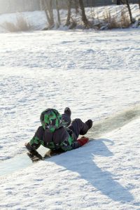 a child is laying in the snow on a snowboard